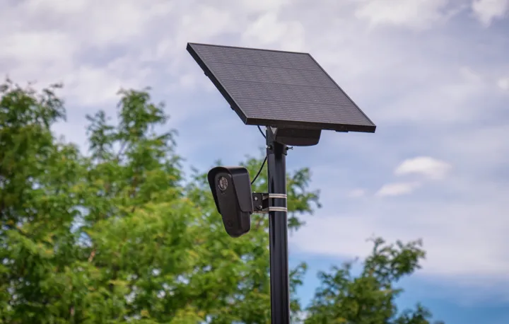 A black license plate reader camera on a pole, a solar panel above it